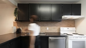 A modern kitchen with dark cabinets, a white stove, and a dishwasher. - Unit 26 - Ski-in/Ski out at Mont-Sainte-Anne for 8 people (Beaupré)