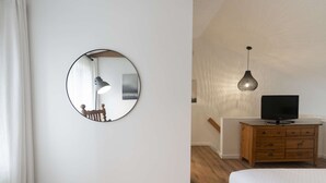 A bedroom with a round mirror, a wooden dresser, a television, and a bed. - Unit 26 - Ski-in/Ski out at Mont-Sainte-Anne for 8 people (Beaupré)