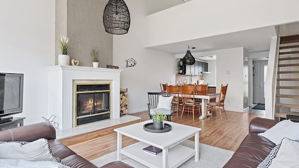 A modern living room with a fireplace, a dining area, and a staircase. - Unit 26 - Ski-in/Ski out at Mont-Sainte-Anne for 8 people (Beaupré)
