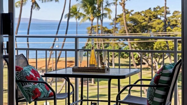 A balcony with a table, chairs, and a bottle of champagne. - Oceanview 1 bedroom condo, AC, walk to everything in the Kihei triangle (Kihei)