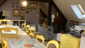 Een eethoek met een lange tafel bekleed met een citroenprint, gele stoelen en een grijze bank.