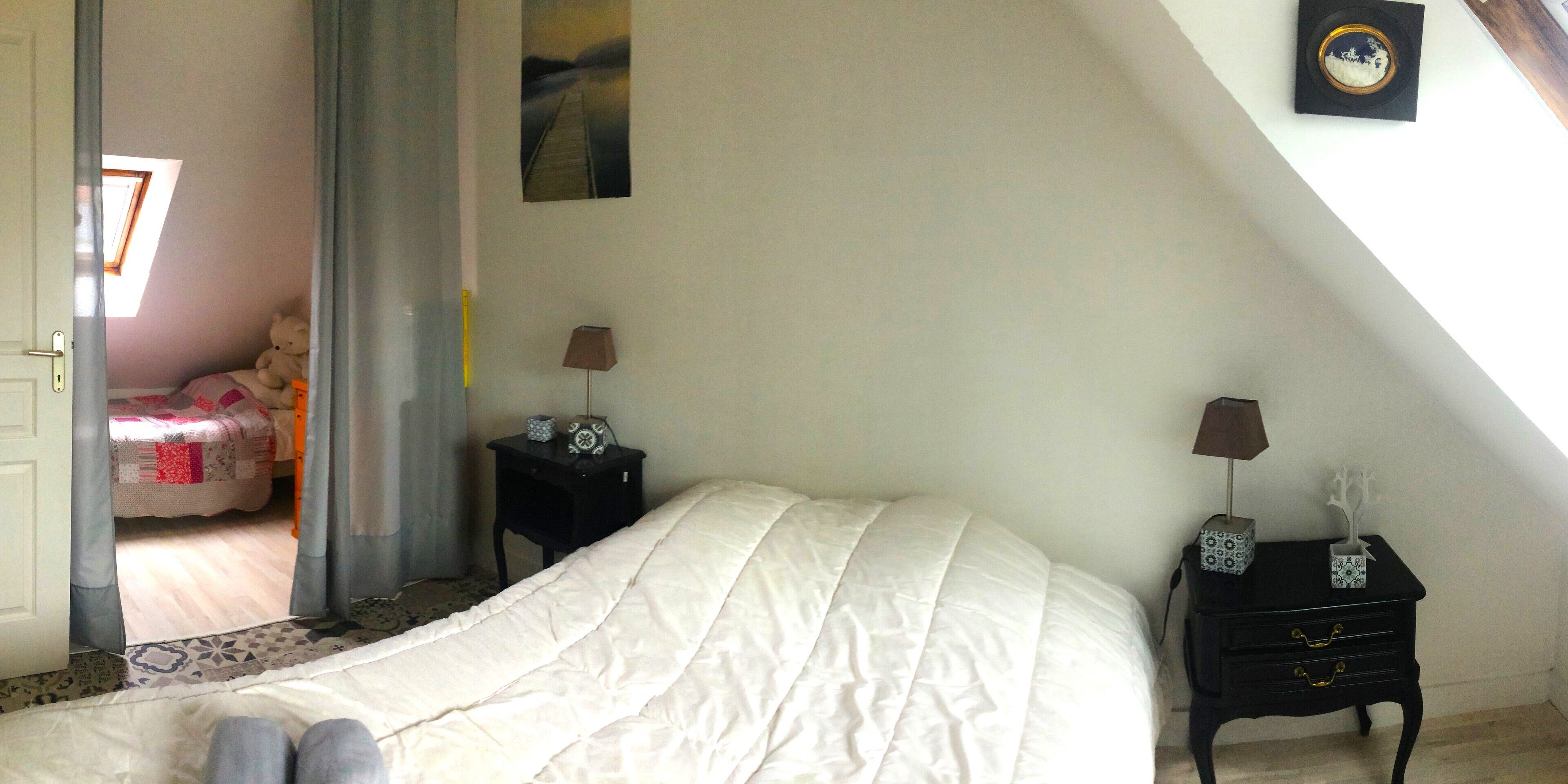 Une chambre à coucher avec un lit, une table de chevet, une lampe et une fenêtre avec des rideaux.