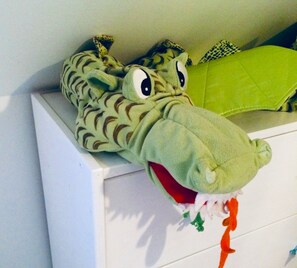 Ein plüschiges Dinosaurier-Kopfspielzeug auf einer weißen Kommode.