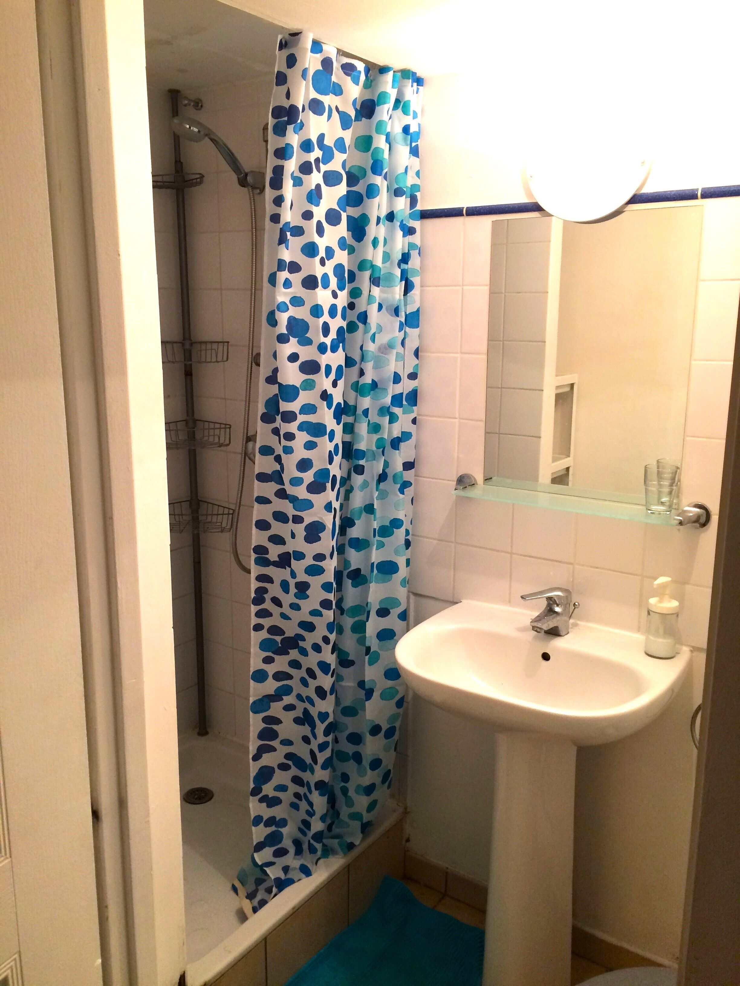 Ein Badezimmer mit Dusche, Waschbecken und Ablagefläche aus Glas.