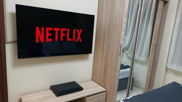 Ett rum med en stor tv-skärm på väggen, där Netflix-logotypen visas.