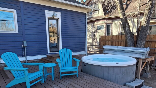 Una terraza con sillas Adirondack azules, un jacuzzi y una mesa de madera.