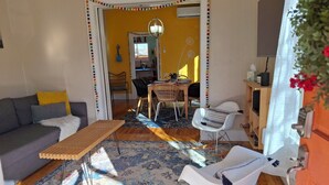Una sala de estar acogedora con un sofá, una mesa de centro, un comedor con sillas y una alfombra estampada.