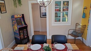 Un área de comedor con un juego de arcade Pac-Man, una araña y una estantería.
