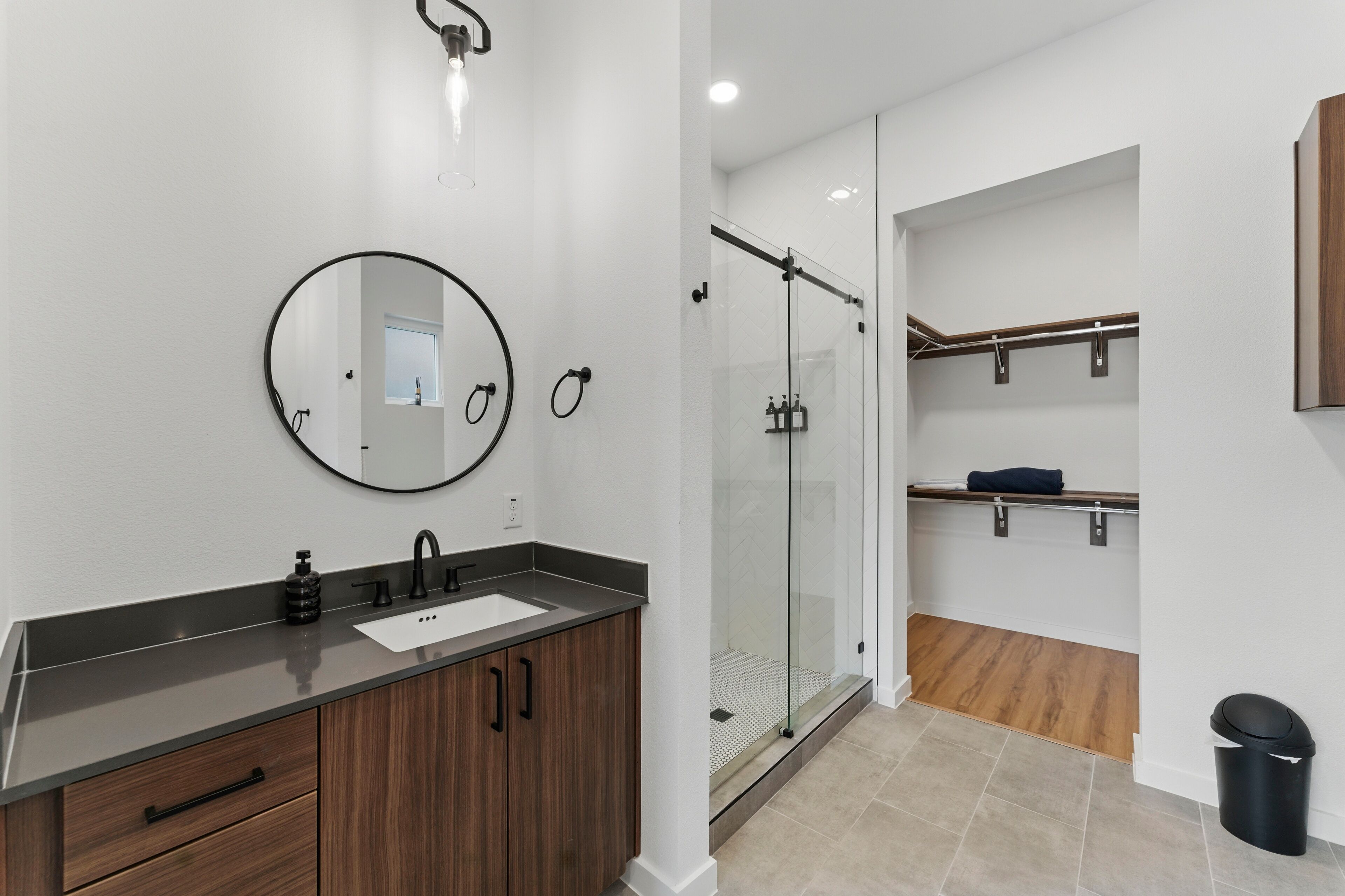 A modern bathroom with a large mirror, a sink, and a glass-enclosed shower.