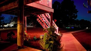 A covered outdoor area with a staircase, plants, and a red-lit structure.