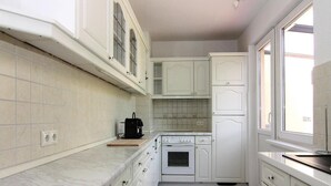 A kitchen with white cabinets, a stove, and a window.
