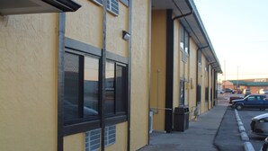 A building with a yellow facade, large windows, and a parking lot with cars. - Extended Stay Warrenton Inn (Warrenton)