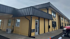 A yellow building with a black roof, a door, and windows. - Extended Stay Warrenton Inn (Warrenton)