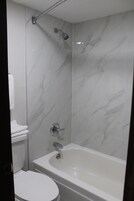 Bañera con ducha, toallas, jabón, shampoo