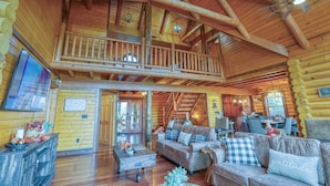 Un intérieur spacieux de chalet en bois, doté d’un balcon, de planchers en bois et d’un coin repas.