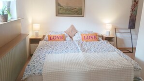 A bedroom with a bed, two nightstands, a painting above the bed, and a radiator on the left. - Vacation apartment Erika (Badenweiler)