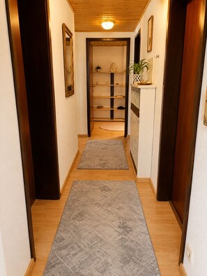 Un pasillo con suelo de madera, un mueble empotrado y una puerta que da a otra habitación.
