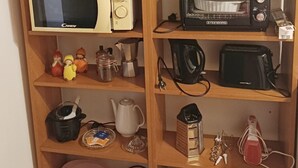 Une cuisine avec des étagères en bois, un four à micro-ondes, un grille-pain et divers ustensiles de cuisine.
