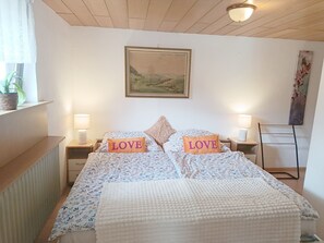Ein Schlafzimmer mit einem Bett, zwei Nachttischen, einem Bild über dem Bett und einem Heizkörper links.