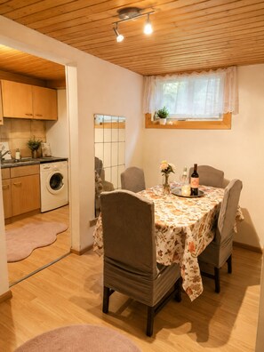 Cocina funcional con armarios de madera, lavadora y comedor con mesa para dos.