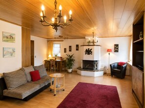 Una sala de estar acogedora con un sofá, una alfombra roja, una chimenea y un televisor.