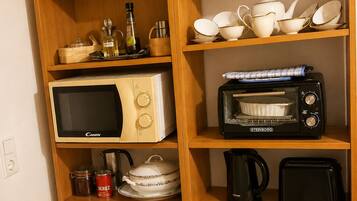 Eine Küche mit Holzregalen, auf denen verschiedene Küchenutensilien, eine Mikrowelle, ein Toaster und ein Wasserkocher stehen.