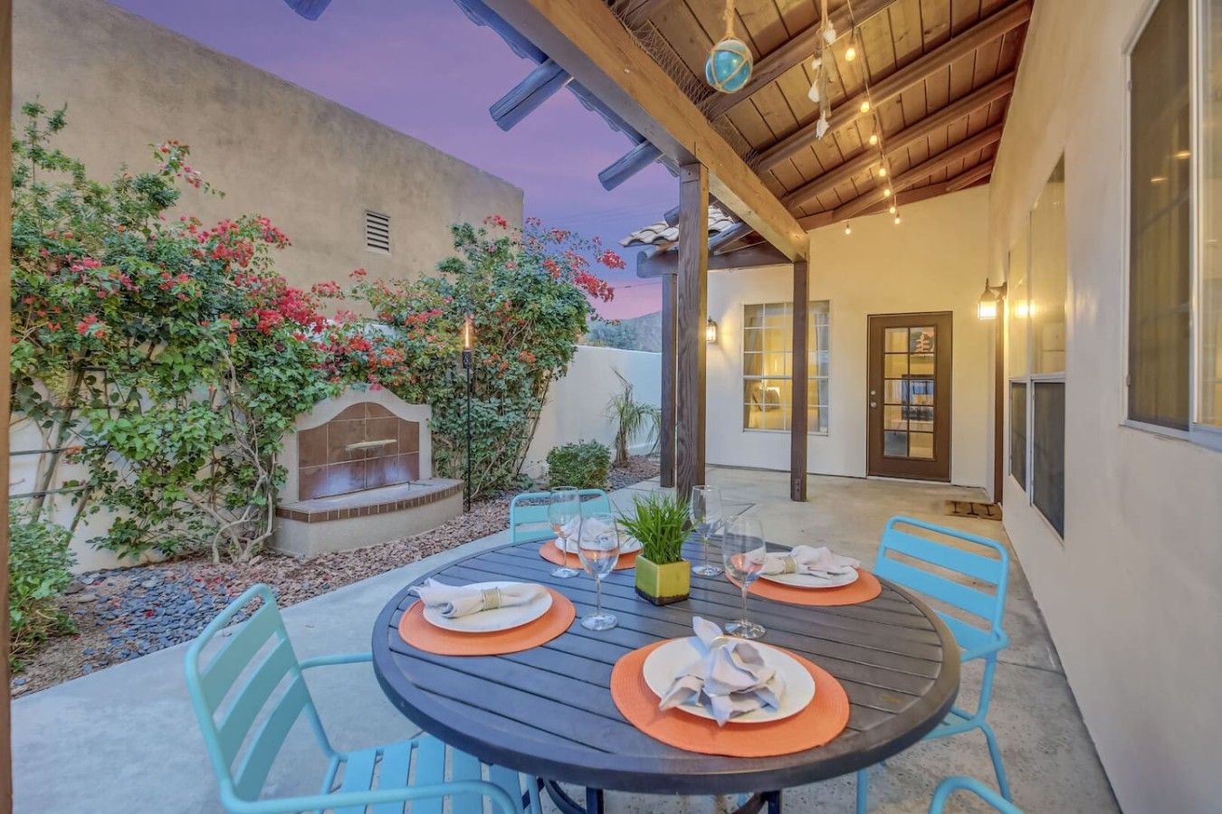 Une terrasse extérieure avec une table ronde préparée pour les repas, entourée de chaises, et un barbecue intégré.