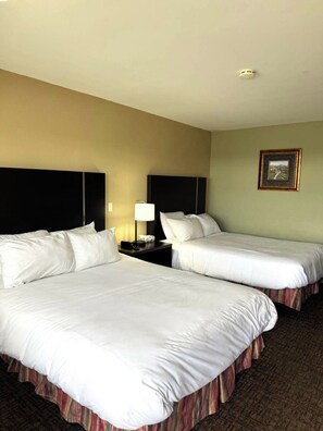 A hotel room with two beds, a nightstand with a lamp, and a framed picture on the wall. - Fundy Line Motel (Miramichi)