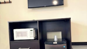 A kitchenette with a microwave, refrigerator, and a flat-screen TV mounted on the wall. - Fundy Line Motel (Miramichi)