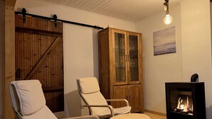 Una habitación acogedora con una cama, dos sillones, un armario y una chimenea.