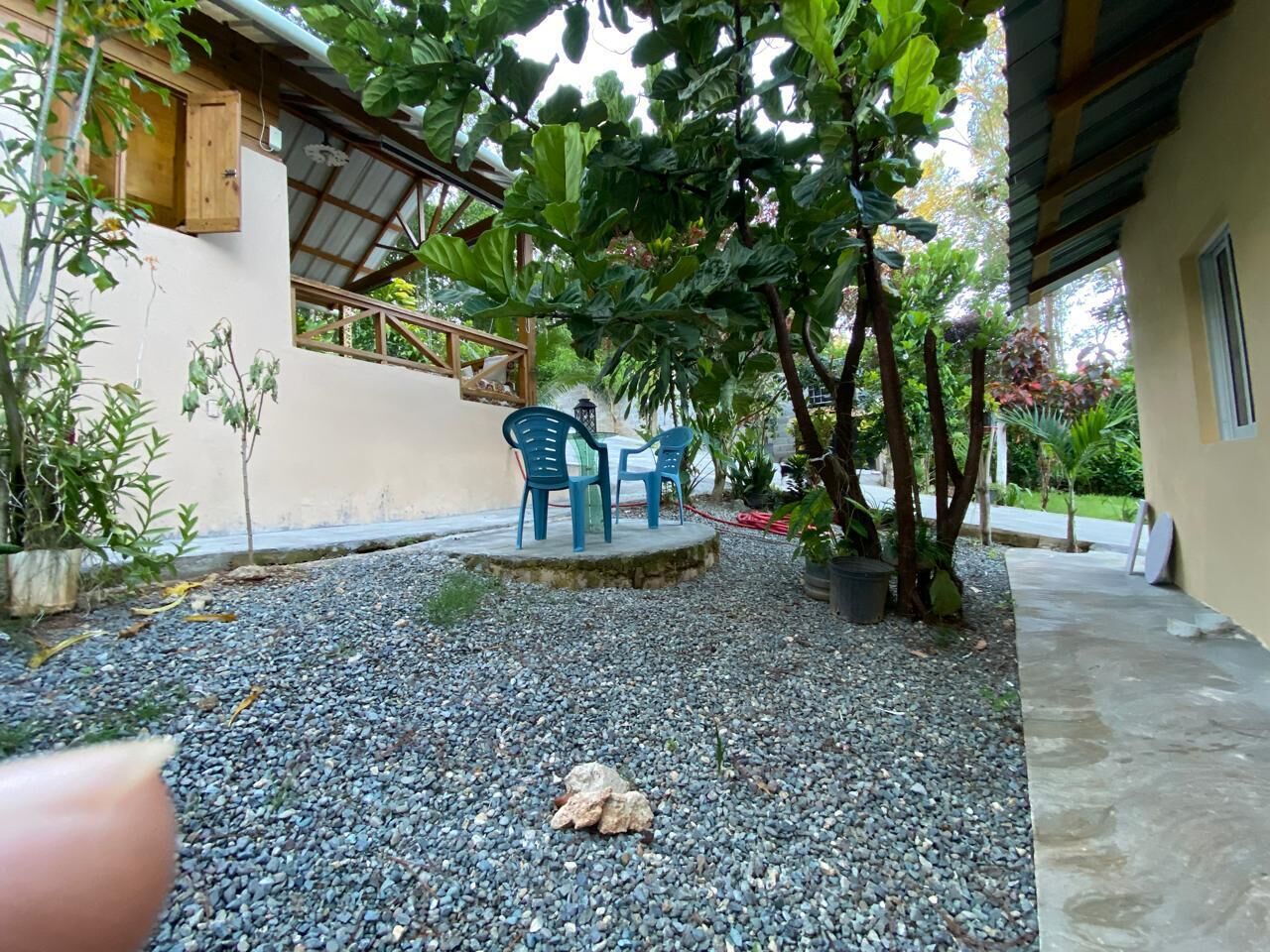 Un espace extérieur aménagé en terrasse, avec un sol recouvert de gravier, deux chaises en plastique bleues et une petite table.