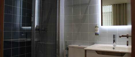 A bathroom with a glass-enclosed shower, a white sink, and a mirror above the sink.