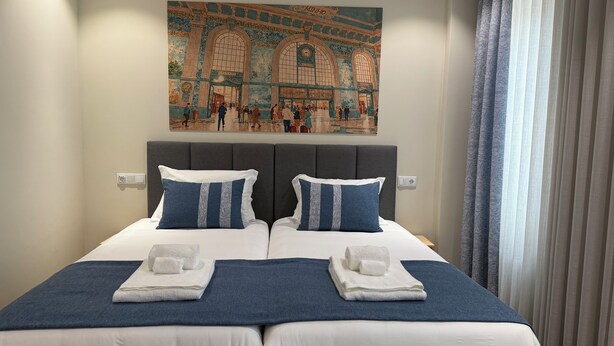 Ein Hotelzimmer mit einem großen Bett, zwei Kissen, einem Kopfteil und einem Gemälde darüber.