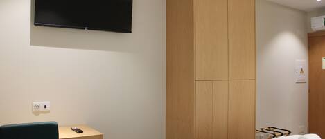 A hotel room with a bed, a desk, a television, and a wardrobe.