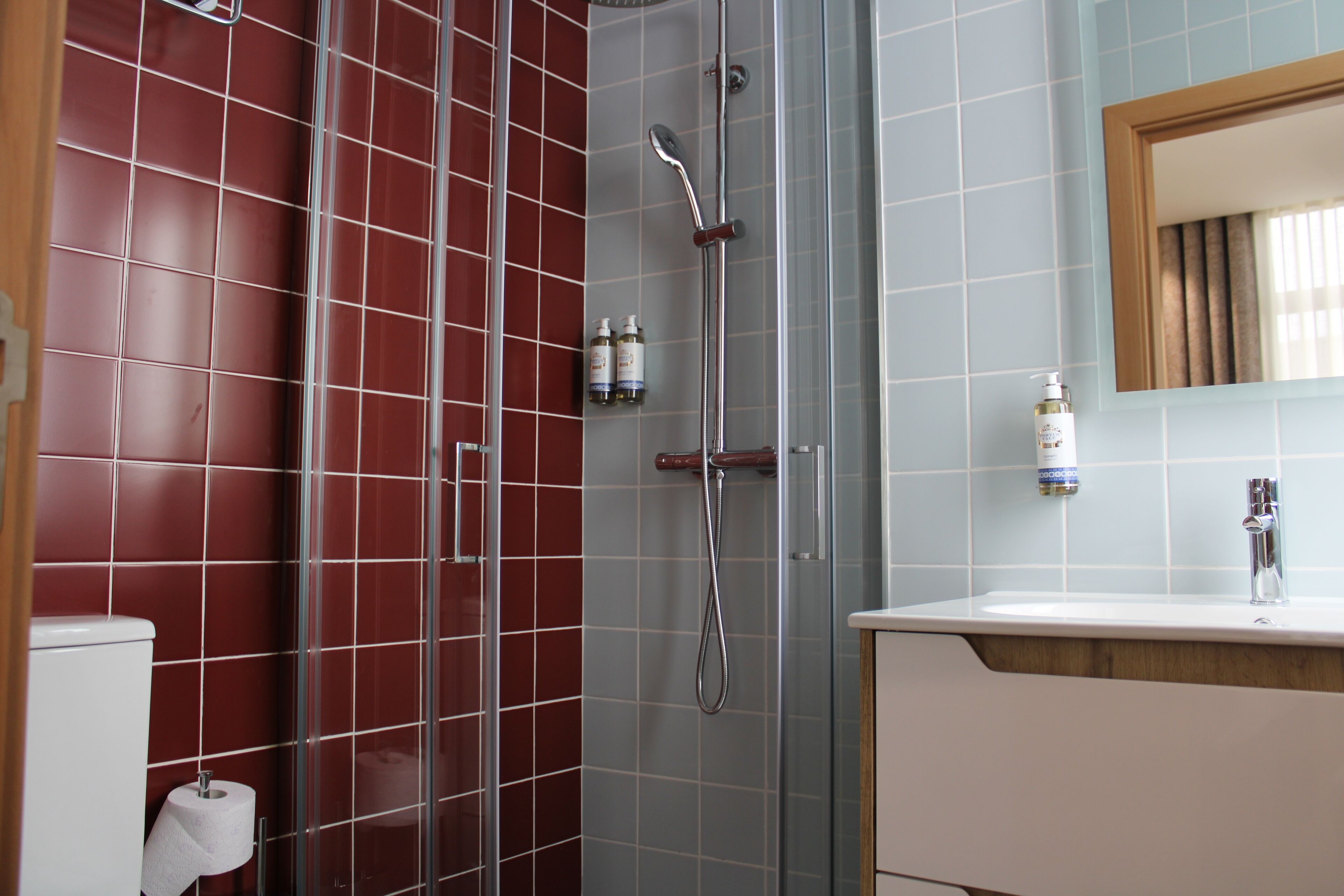 A bathroom with a glass-enclosed shower, a white sink, and a mirror above it.
