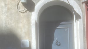 A dark blue door with a small window, a mail slot, and a wall-mounted electrical box. - The Odeon Terrace (Catania)