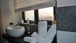 A bathroom with a large white sink, a mirror, and neatly folded towels on the counter. - The Odeon Terrace (Catania)