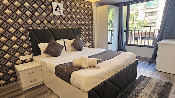 A modern bedroom with a bed, bedside tables, a wardrobe, and a view of the outside. - Astha Kandivali Service Apt (Mumbai)