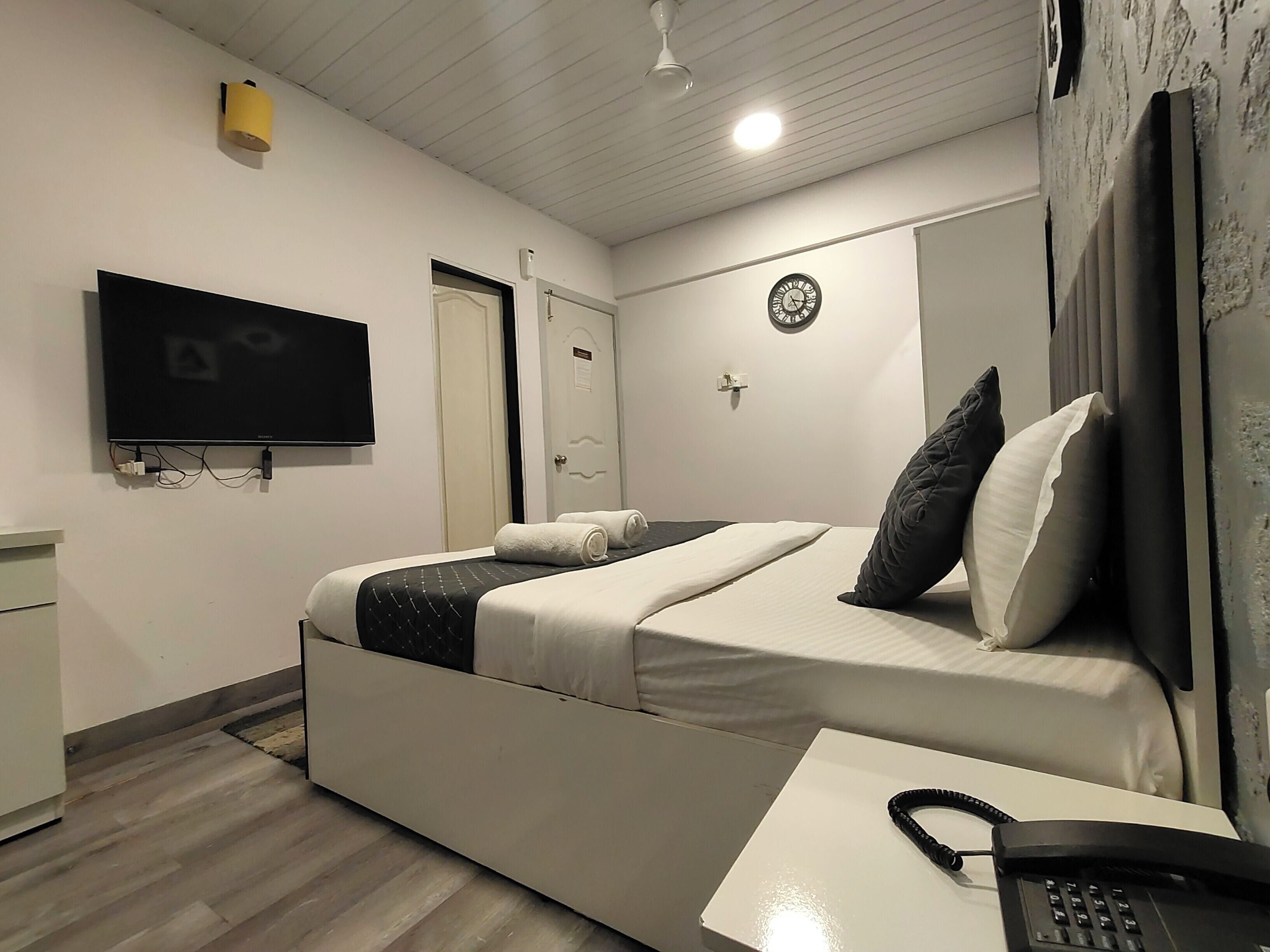 Une chambre à coucher avec un lit, une télévision, une horloge et un téléphone.