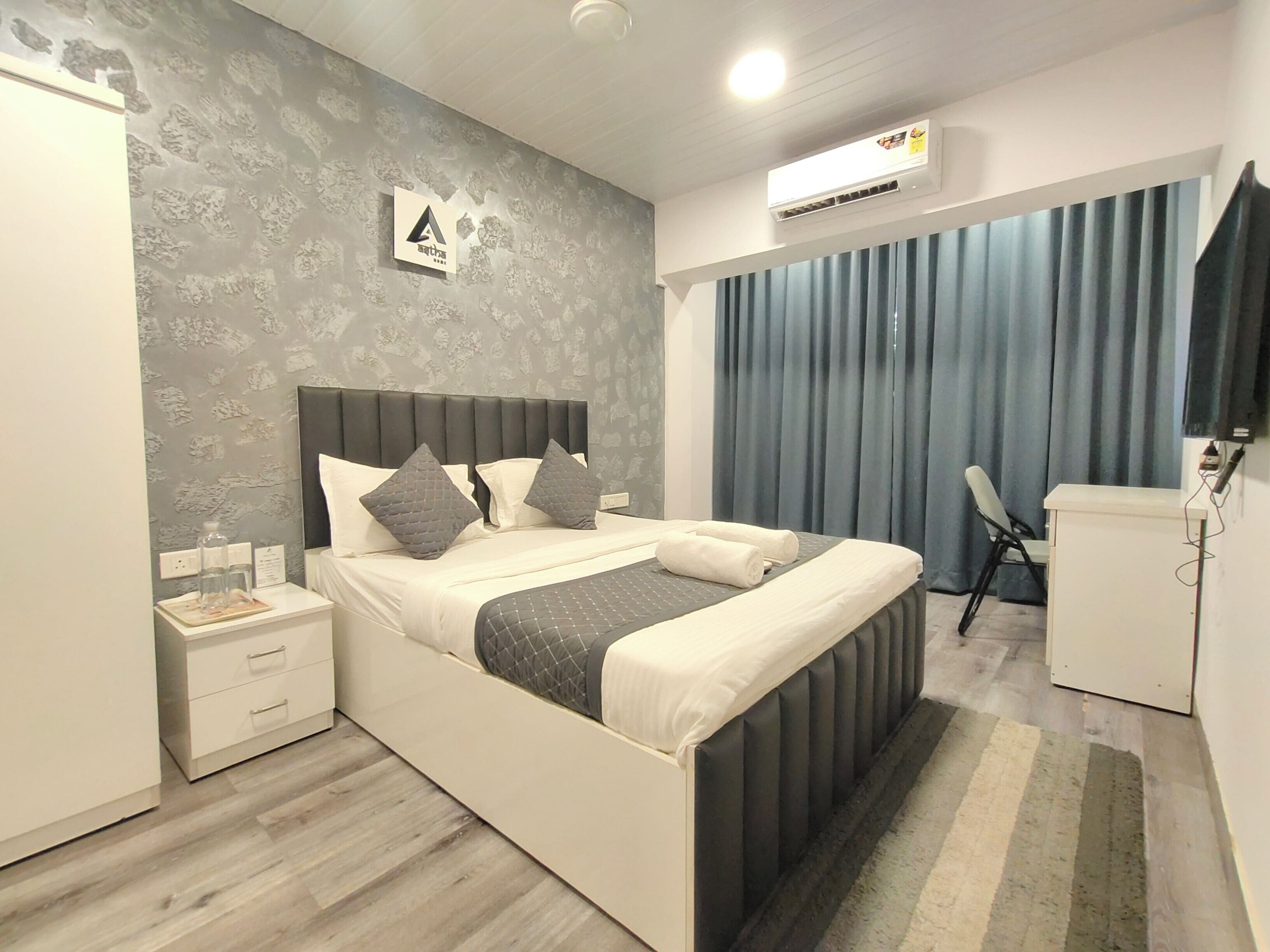 A modern bedroom with a bed, bedside tables, a desk, and a chair.