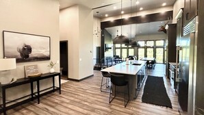 A modern kitchen with a large island, pendant lighting, and a view to the dining area. - Modern Pines-6 Bedroom, 5.5 Bath. 4 Master Suites! (Lead)
