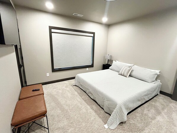 Quarto com cama, mesa de cabeceira, escrivaninha e cadeira.