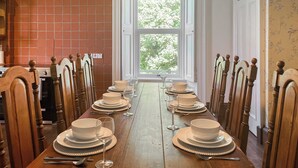 A dining room with a long wooden table set for a meal, flanked by chairs with ornate wooden designs. - West Nevay Farm House (Newtyle, near Blairgowrie)