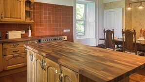 A kitchen with wooden cabinets, a large island, and a dining area with a table and chairs. - West Nevay Farm House (Newtyle, near Blairgowrie)