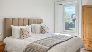 A neatly made bed with a striped throw, a headboard, and multiple pillows, including heart-patterned ones. - West Nevay Farm House (Newtyle, near Blairgowrie)