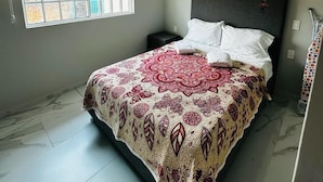Een slaapkamer met een bed, een raam en een nachtkastje.