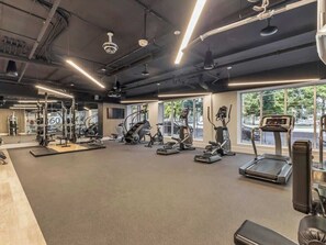 A modern gym with various cardio machines, weightlifting equipment, and large windows providing natural light. - Cozy city retreat w/king bed & fire pit (Salt Lake City)