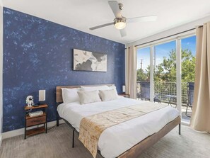 A bedroom with a large bed, a ceiling fan, a nightstand with a lamp, and a view of the outdoors through a sliding glass door. - Cozy city retreat w/king bed & fire pit (Salt Lake City)