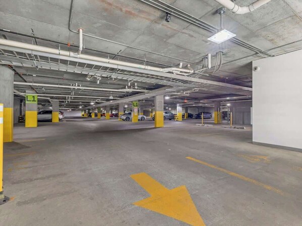 Un aparcamiento subterráneo con varios niveles, plazas delimitadas y flechas direccionales en el suelo.