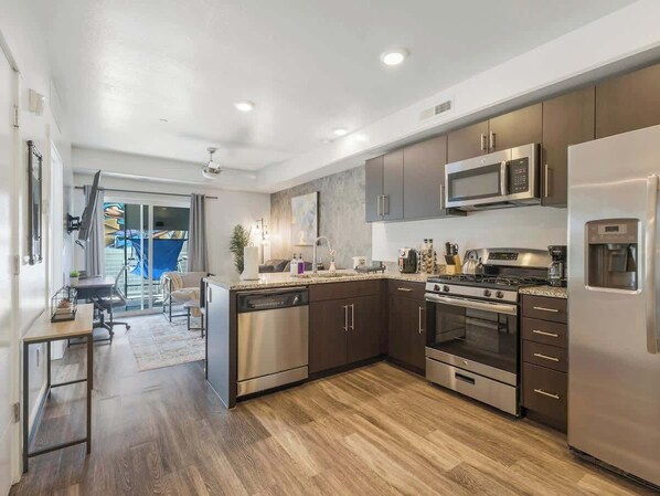 Una cocina moderna con electrodomésticos de acero inoxidable, suelo de madera y una zona de comedor con vistas.